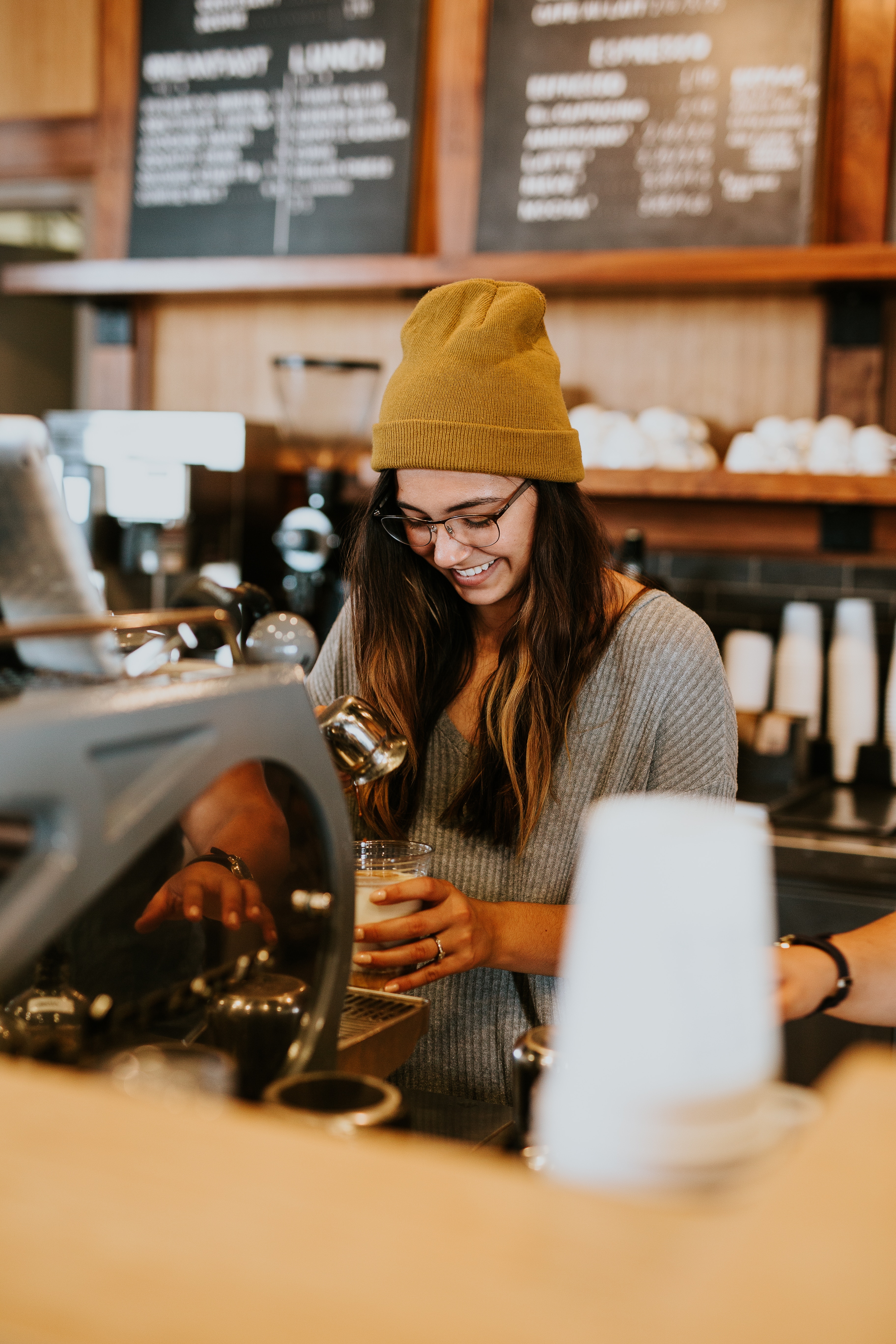Happy student smiling while making coffee at a coffee shop